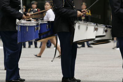 Midsection of musicians playing drum on street during parade