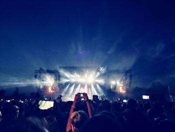 Crowd at music concert against sky at night