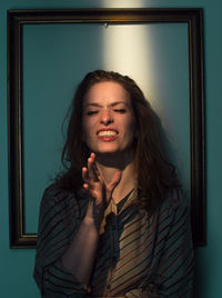 Mid adult woman standing against picture frame on wall