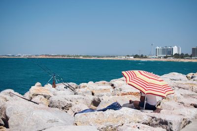 Flag by sea against clear blue sky