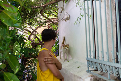 Side view of young man looking at standing by flower tree