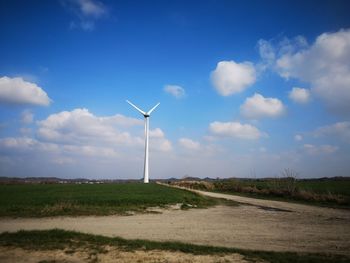 Wind turbines on field against sky