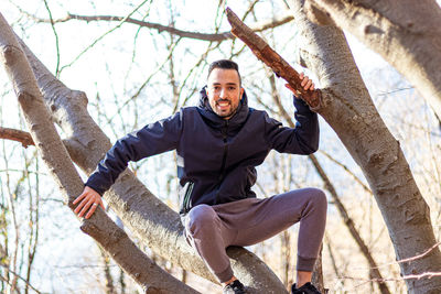 Portrait of young man against tree trunk