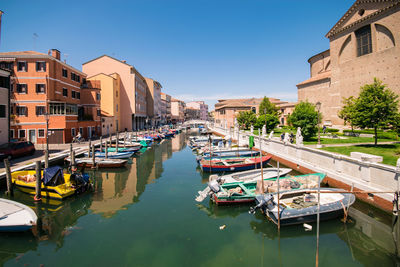 Boats moored in canal amidst buildings against clear sky