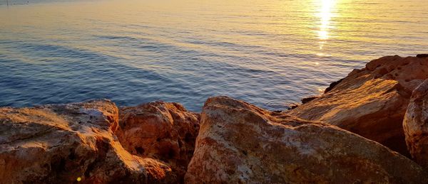 Rock formation on beach against sky during sunset