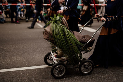 Low section of woman with baby carriage walking on street