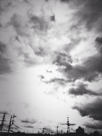 Low angle view of power lines against cloudy sky