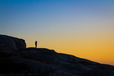 Silhouette man standing on cliff against clear sky
