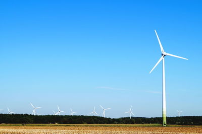 Wind turbines on field against clear sky