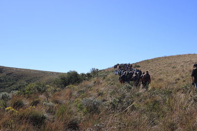 People on arid landscape against clear blue sky