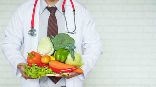 Midsection of doctor holding vegetables