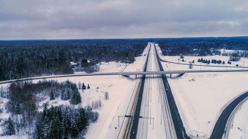 Snow covered road by trees against sky