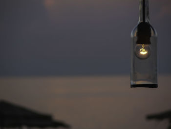 Close-up of illuminated lamp on sea against sky