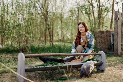 Smiling woman feeding hen at farm