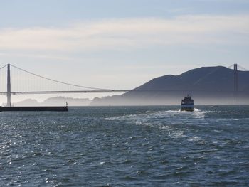 View of suspension bridge over sea against sky