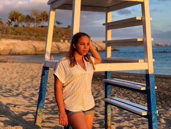 Portrait of beautiful young woman sitting on beach