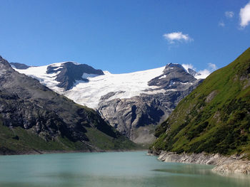 Scenic view of lake and snow covered mountains against sky