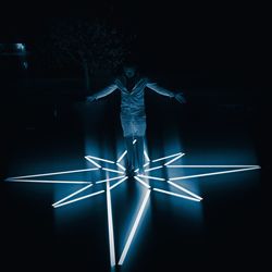 Low angle view of illuminated lighting equipment against black background