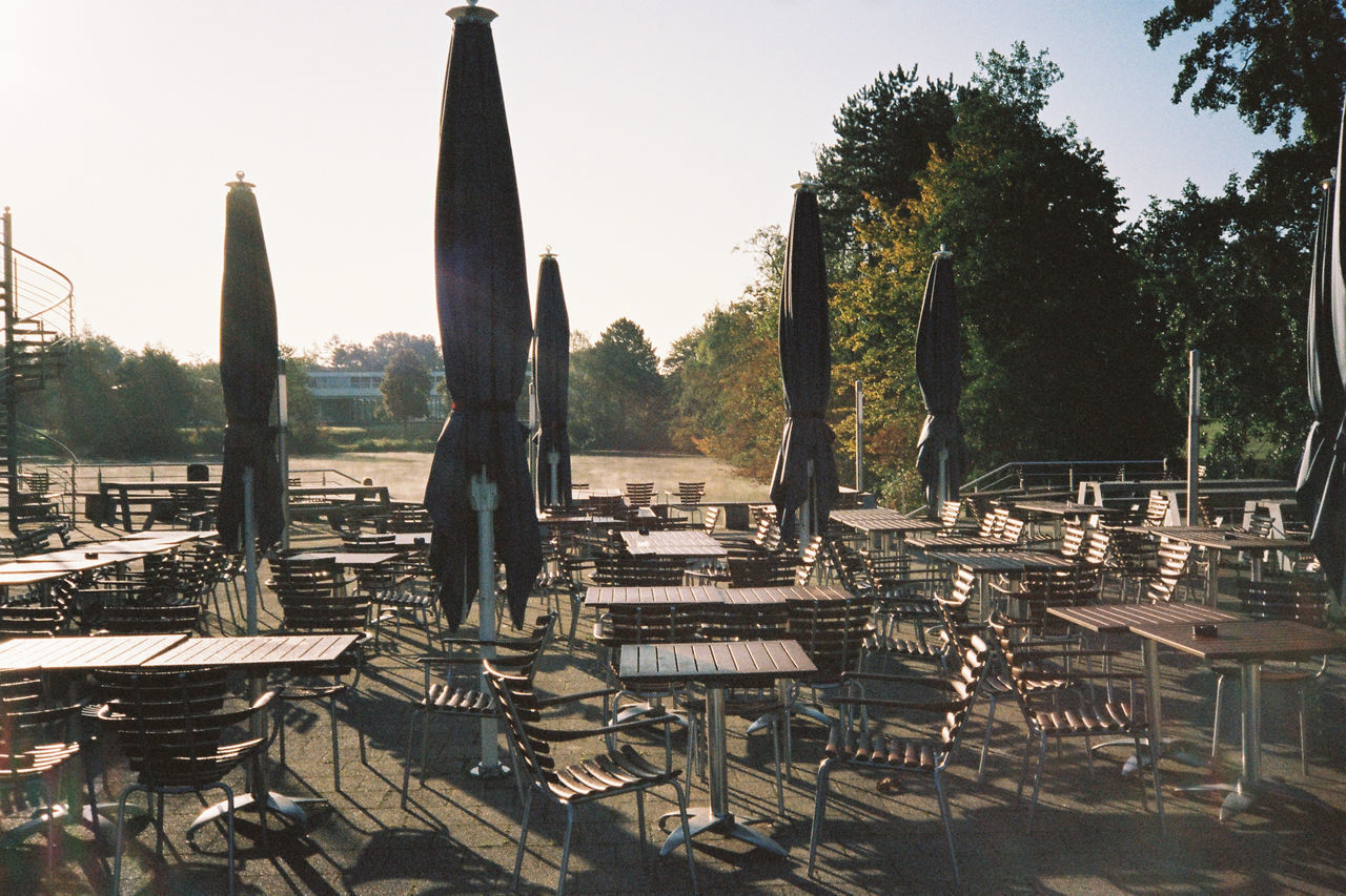 EMPTY CHAIRS AND TABLE AGAINST CLEAR SKY