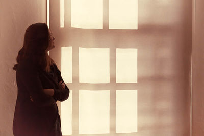 Thoughtful woman with arms crossed looking at wall