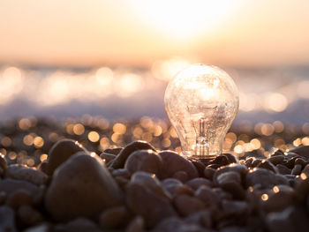 Close-up of illuminated light bulb against sky