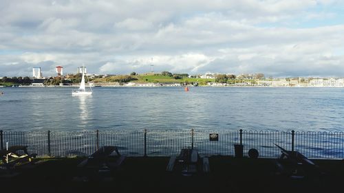 View of city at waterfront against cloudy sky