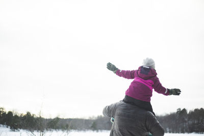 Full length of woman with arms raised against sky during winter