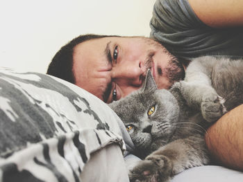 Portrait of man and cat relaxing on bed at home