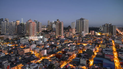 Aerial view of illuminated cityscape against clear sky