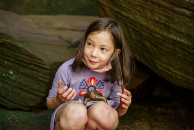 Portrait of smiling girl holding while sitting outdoors