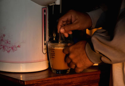 Close-up of man holding coffee cup on table