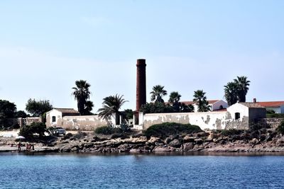 Buildings by sea against sky