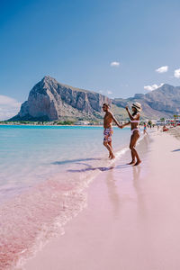 People on beach by mountain against sky