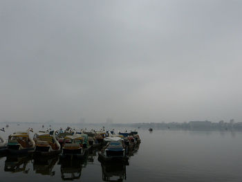 Swan boats on west lake in hanoi, vietnam against cloudy sky