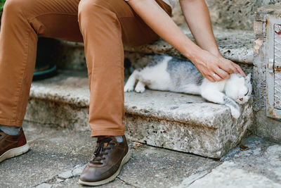 Low section of person with cat relaxing outdoors
