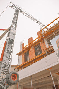 Low angle view of crane by building against clear sky