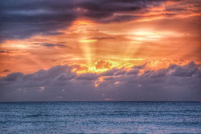 Scenic view of sea against cloudy sky at sunset