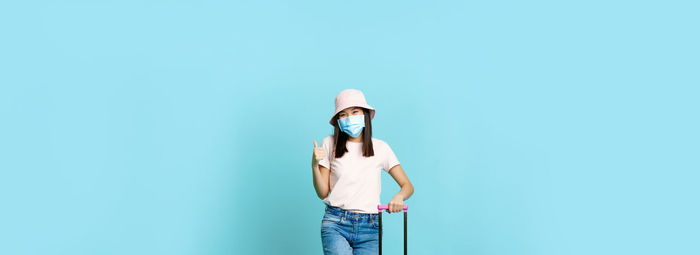 Portrait of woman standing against blue background