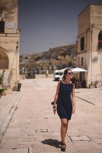 Full length of woman standing on footpath in city