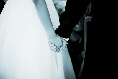 Midsection of couple holding hands in wedding ceremony