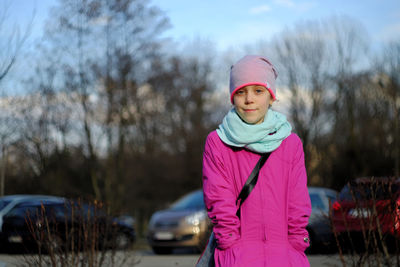 Portrait of girl wearing knit hat against cars