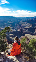 Rear view of woman sitting on rock while looking at mountains in grand canyon national park