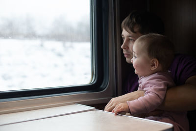 Rear view of boy looking through train window