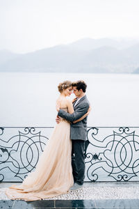 Friends standing on railing against sea