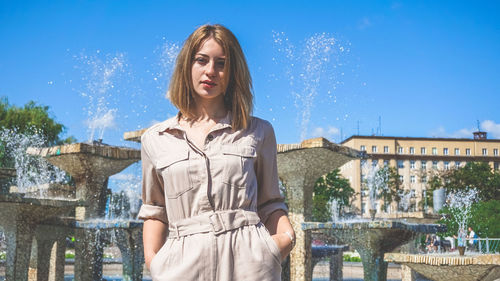 Young woman standing against blue sky