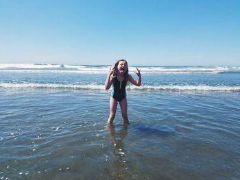 Portrait of young woman standing on beach against sky