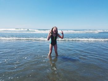 Portrait of young woman standing on beach against sky