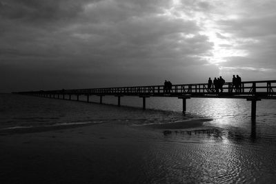 Pier on sea against cloudy sky