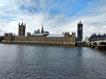 View of buildings by river against sky in city