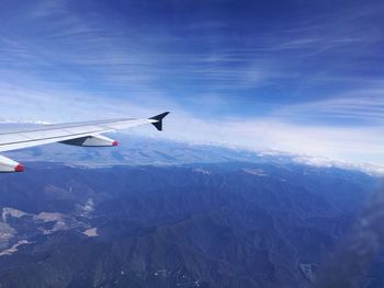 Airplane flying over snowcapped mountains against sky